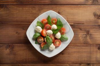 caprese salad in plate at wooden  background