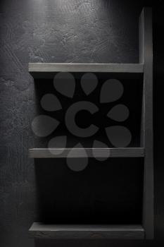 shelf and black wall on wooden background