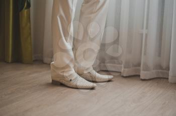 Feet of the man in white trousers and shoes.