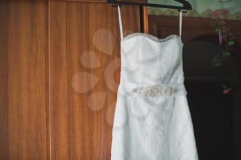 The wedding dress hangs on a door.