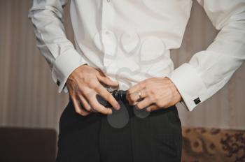 The groom dresses a white belt and trousers.