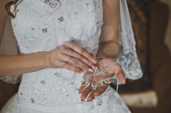 The bride holds earrings.