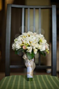 Bouquet from beige flowers on a wooden chair.