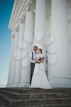 The bride and groom on the background of white columns.