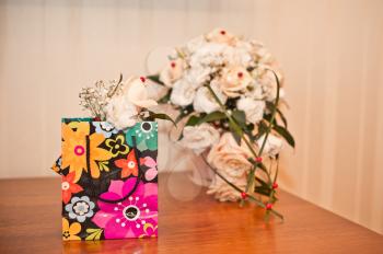Gift package and flowers on a table.