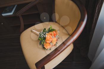 A bouquet of flowers lies on a beige chair.