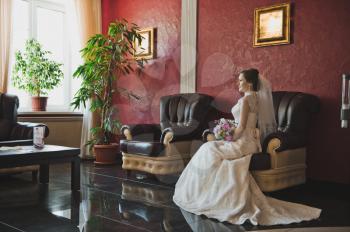 The bride in a gorgeous dress sits and waits.