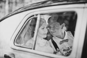 The bride and groom in the cabin of the old car.