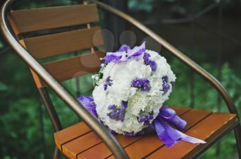 Bouquet from violet flowers on a wooden chair.