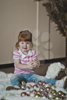 Redhead girl playing with Christmas balls.