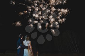 Newlyweds hugging on the background of fireworks.