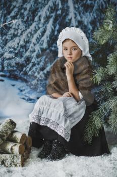 The child sits pensively in the winter woods.