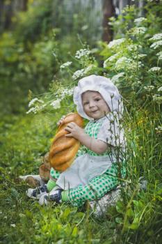 The child in the clothes of a Baker eats the baton.