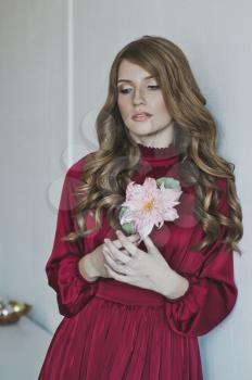 Portrait of a girl in a red dress with a red flower.