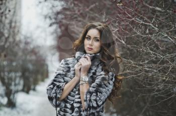 Beautiful girl in a fur coat on a winter walk.