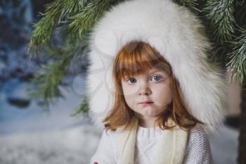 Portrait of a child under the winter tree.