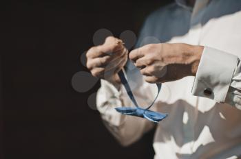 A man adjusts blue tie.