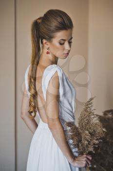Beautiful girl in open dress with long blond-brown plait of hair.