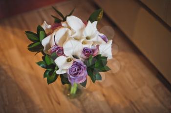A beautiful bouquet of flowers stands in a vase on the floor.