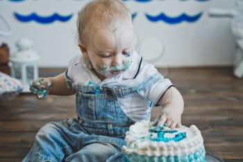 Little boy eats with his hands on the cake.