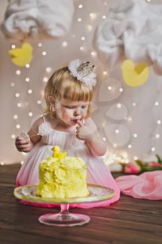 The girl tastes the cake on their first birthday.