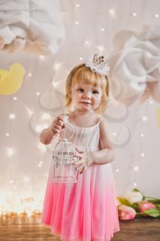 A little girl with a white bird in the cage.