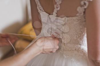 The process of tying the lace on the dress.