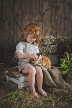 Little girl playing with a red rabbit.