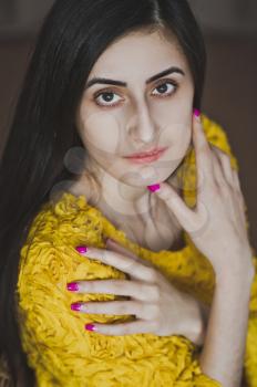 Portrait of a girl with long hair in yellow shirt.