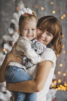 Joyful mother playing a daughter on the eve of the new year.