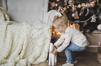 A child plays with a horse and Christmas trees.