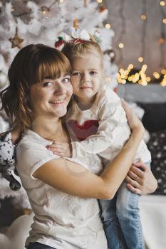 Tender family hug of a mother and daughter have Christmas trees.