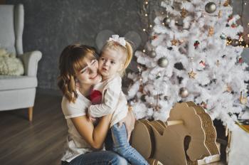 The embrace of a mother and daughter near the Christmas tree.