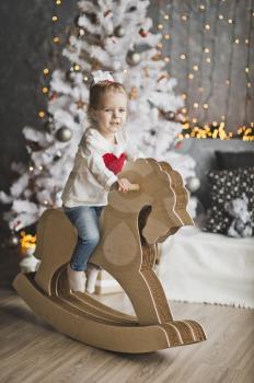 Little girl riding a toy horse.