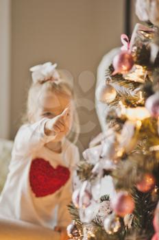 Baby playing with decorations on a Christmas tree.