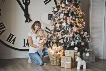 Mother and her daughter on background of great white watches and Christmas trees.