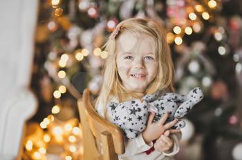 Close-up portrait of blond little girl on the Christmas lights.