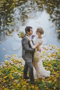 The couple dream of the future standing on the shore of fall lake.