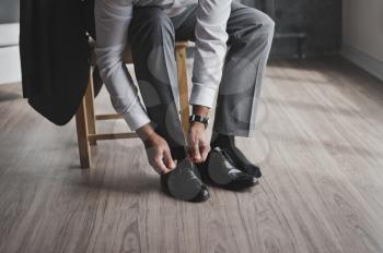 The process of tying the laces on mens Shoe.