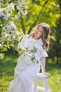 The girl in the position dressed in white resting in a beautiful garden.