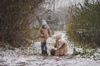Girl and boy on a walk with the dog breed Samoyed.