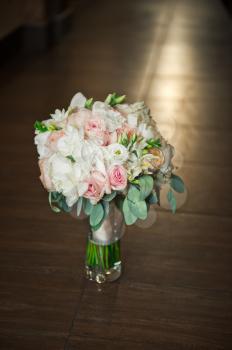 A bouquet of roses in a vase on the floor.