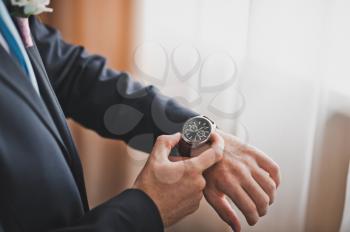 A man in a suit wears a watch on his arm.