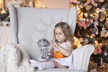 Year-old girl sits in a big gray chair.