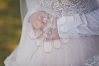 The man hugs the brides waist, closed with a veil.