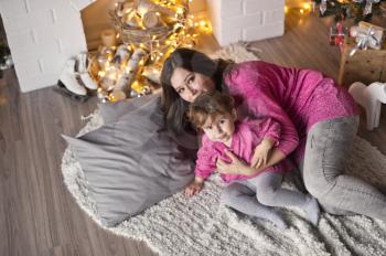 The girl and her mother lying on a blanket near the Christmas tree.