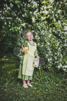 The child with a small watering can in hand walking in the spring garden.