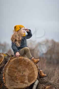 Portrait of a girl sitting on a huge felled tree.