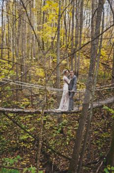 Portrait of young couple standing in the middle of a rickety hanging bridge far above the ground.