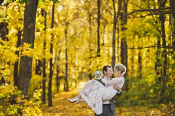 The bride and groom in a modern outfits for a walk on a bright autumn forest.